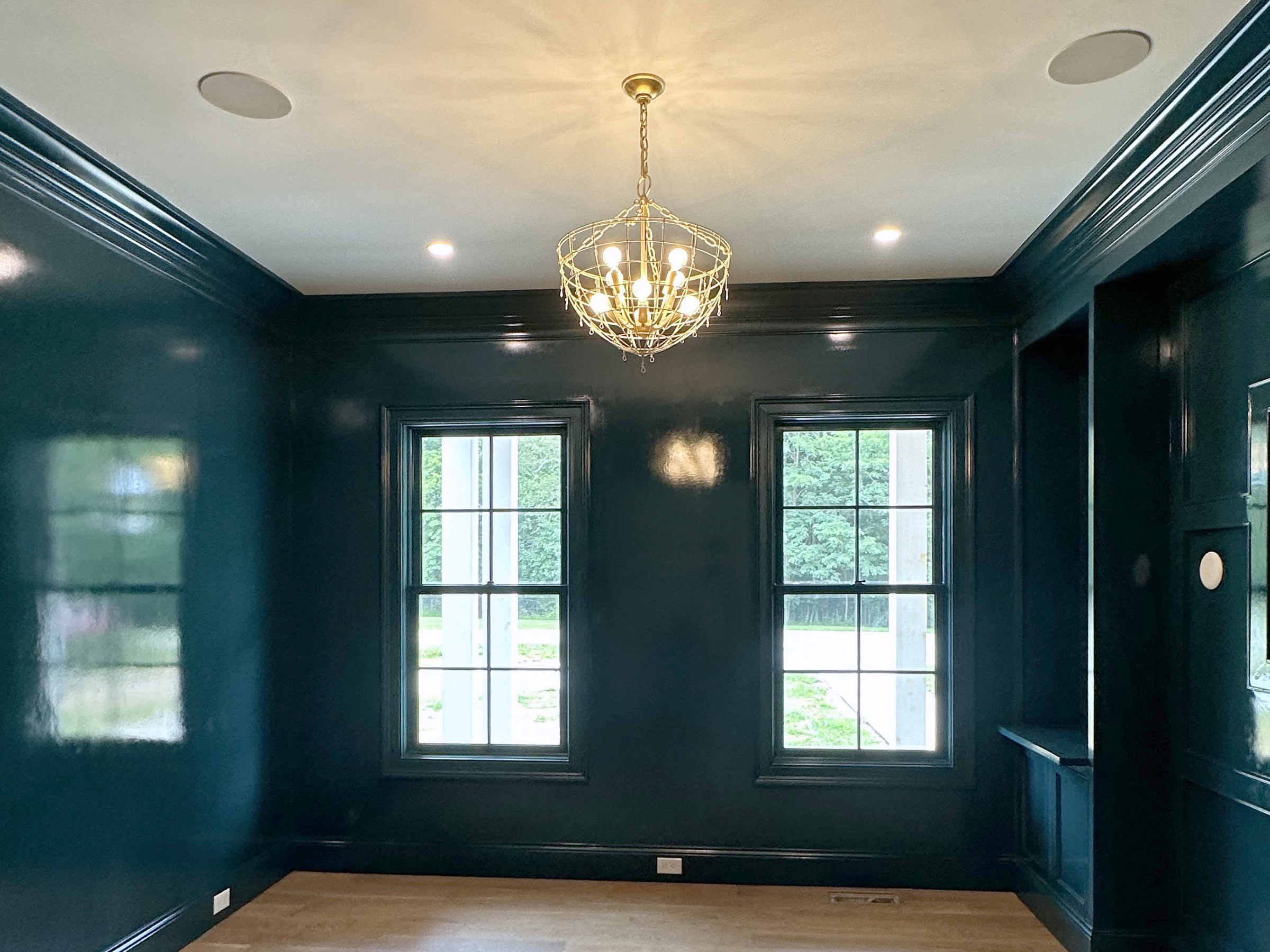Room with deep green paneled walls and a chandelier